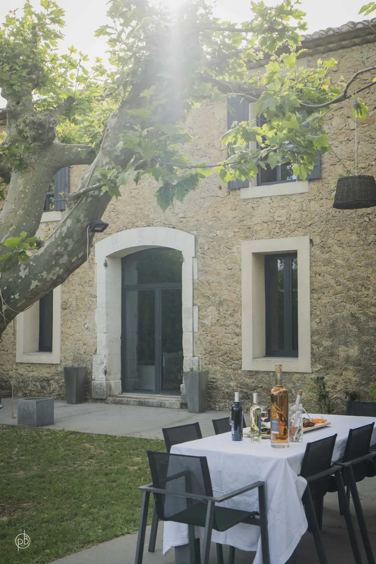 Façade en pierre, table dressée et jardin ombragé